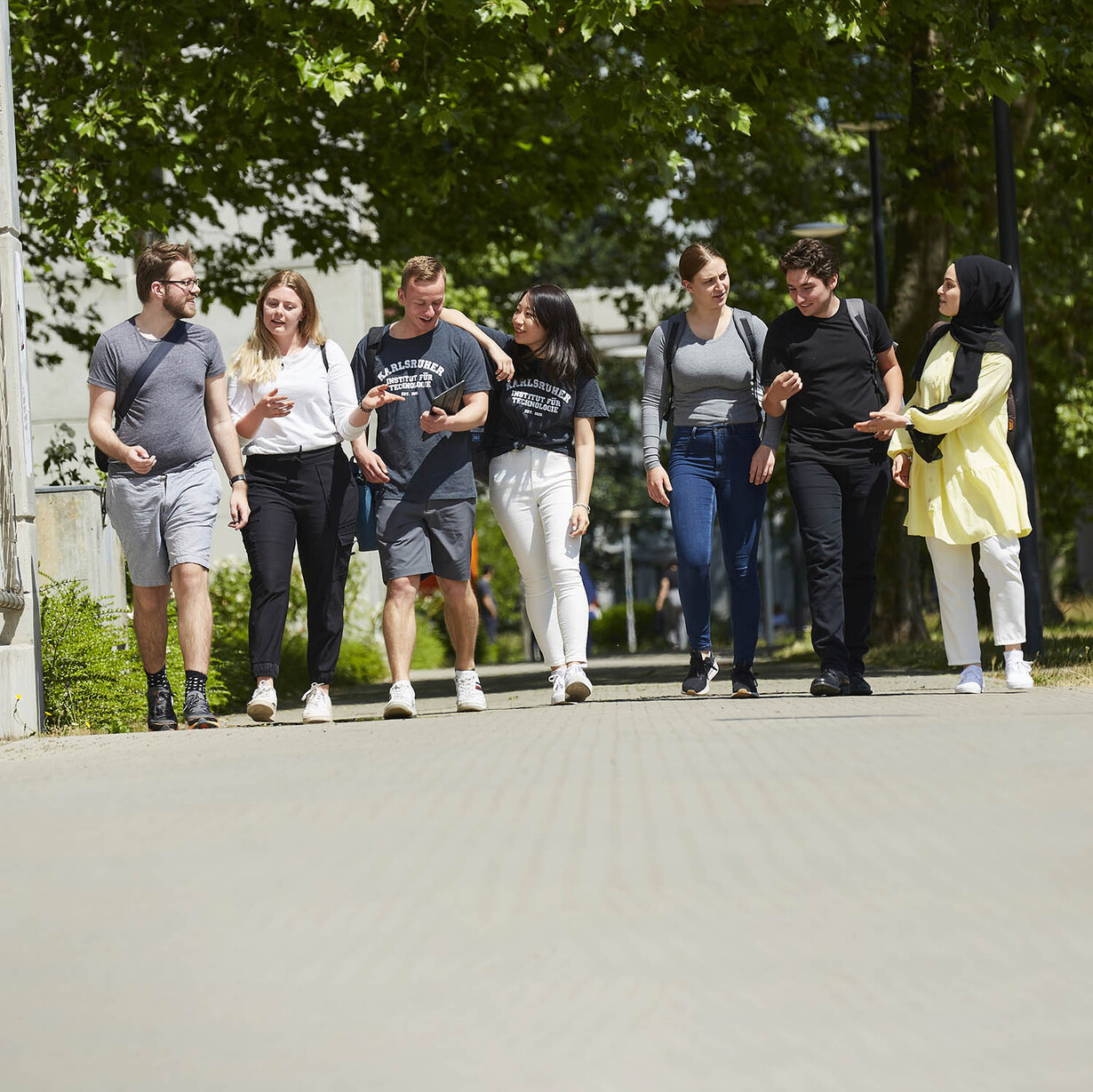 eine Gruppe von 7 jungen Menschen unterhält sich und läuft dabei über den Campus Süd des KIT