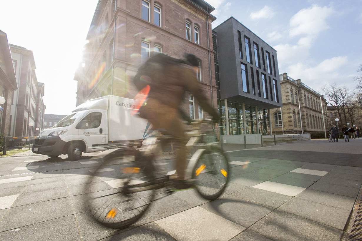 Ein Fahrradfahrer fährt im Sonnenlicht über den Campus Süd